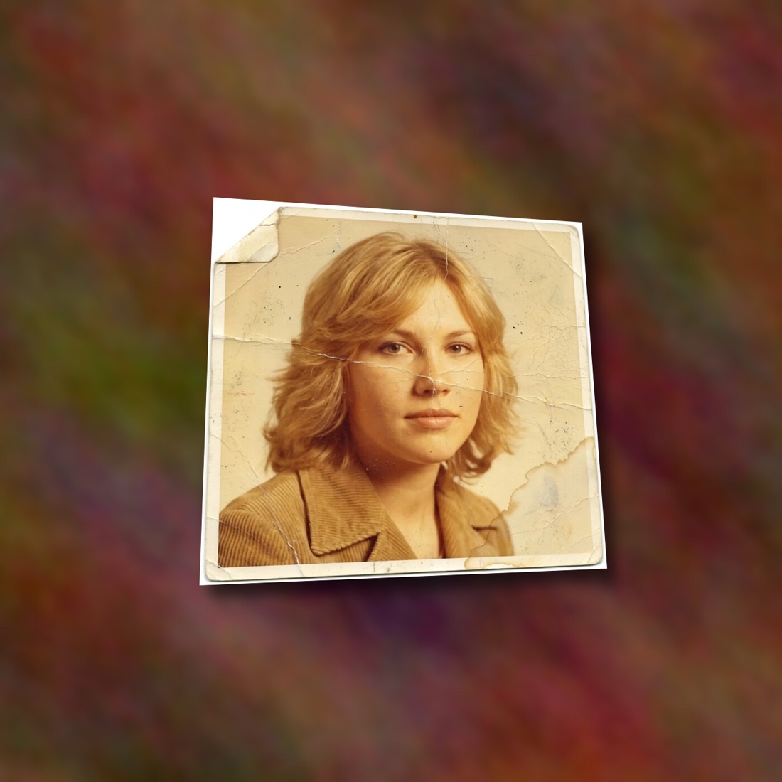 A damaged print photographed crooked on a wooden table with a phone